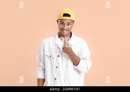 Young African-American guy with chewing gum on color background Stock Photo