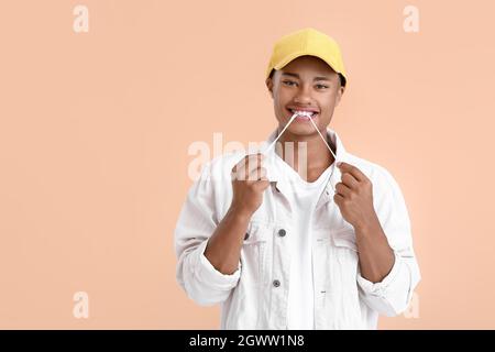 Young African-American guy with chewing gum on color background Stock Photo