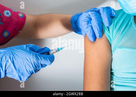 children's nurse injecting arm of little brown girl, doctor's hands with rubber gloves injecting covid-19 or flu vaccine. medical, health and pandemic Stock Photo