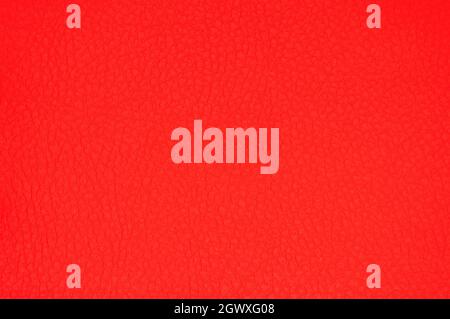 Framgent of genuine leather artificially dyed bright red with vignetting along the edge. Background, pattern, texture. Stock Photo