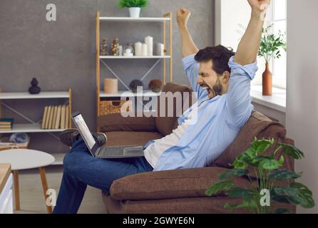 Sleepy tired young man stretching arms and yawning while working on laptop at home Stock Photo