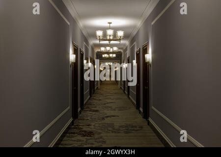 Empty luxurious hotel corridor lit by chandeliers Stock Photo