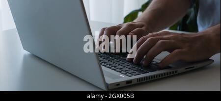 Close up young man working on laptop. Work from home banner. Stock Photo
