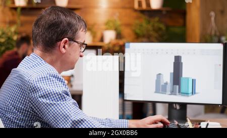 Engineer man working at architectural building prototype on computer using digital company software. Workaholic architect developing industrial construction structure for creativity project Stock Photo