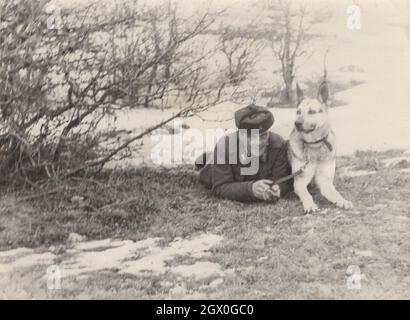 vintage / Retro army / military german shepherd dog series 2. One soldier is  posing with his dog ( German Shepherd ) on the field  around at the 1950's. He is from Eastern Europe possibly Hungary.       Source: original photograph Stock Photo