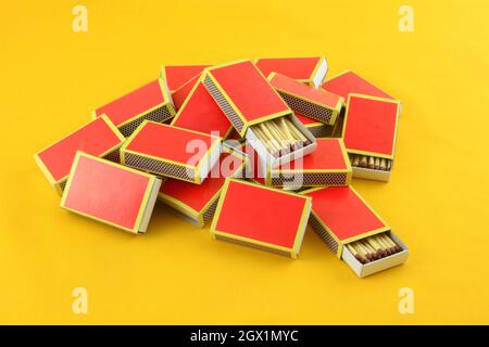 Heap of red boxes of safety matches with two open on yellow background Stock Photo