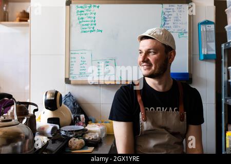 A young man in a cap and apron at the baker's job Stock Photo
