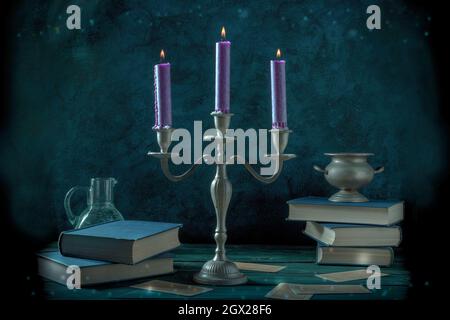 Candle magic. A witch's study with old books, magick potions, and divination cards, toned image Stock Photo