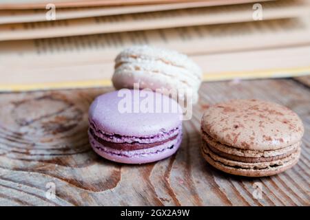 macarons on the background of the book, on a wooden table. horizontal frame. Aesthetics with macaroons and a book. Beautiful cakes on a wooden table Stock Photo