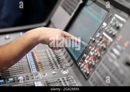 Operator controls digital audio mixing console by touch screen. Selective focus. Stock Photo