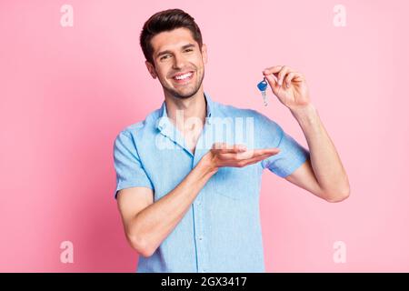 Photo portrait smiling man in blue shirt bought new apartments happy with key isolated pastel pink color background Stock Photo