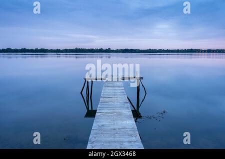 Calm water in the morning on the Danube and pier before sunrise blue hour Stock Photo