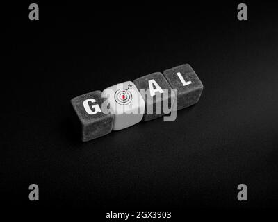 Goals concept. Goal, word and target icon sign on black and white cube blocks and arrow arranging on dark background, top view. Stock Photo