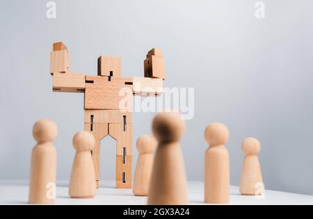 Leadership concept. The Leader or influencer, wooden robot strong power gesture standing among wood human, followers on white background, minimal styl Stock Photo