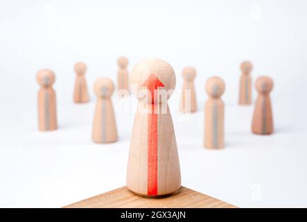 Leader woman, influencer, wooden figures with growth arrows, female standing on the podium and the team on white background, minimal style. Leadership Stock Photo