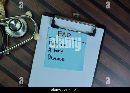 PAD - Peripheral Artery Disease write on sticky notes isolated on Wooden Table. Stock Photo