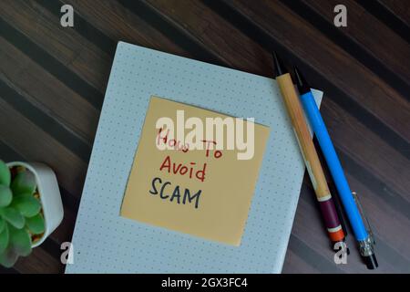 How To Avoid Scam write on sticky notes isolated on Wooden Table. Stock Photo