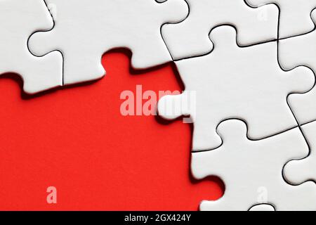 Empty red background surrounded by white jigsaw puzzle pieces with copy space. Stock Photo