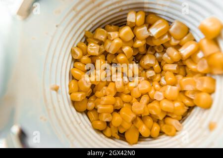 Lots of canned corn in an aluminum can. Close-up top view. Stock Photo