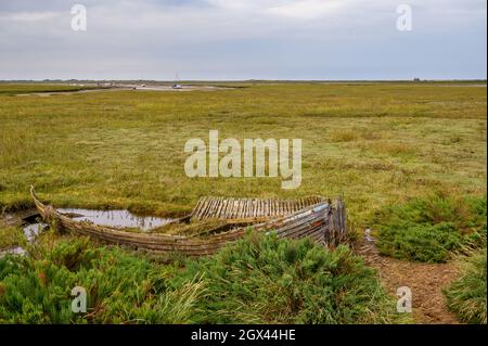 The eroding wreck of a wooden boat laid to rest on the marsh of Blakeney Natural Nature Reserve, Norfolk, England. Stock Photo