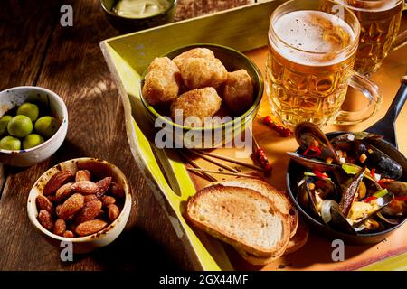 From above of various tasty appetizers and glass cups of cold beer served on wooden table in bar Stock Photo