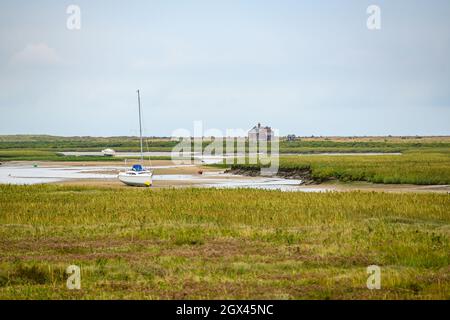 View to Blakeney Watch House over the dry river Glaven with moored sailboats and the marshes in Blakeney Natural Nature Reserve, Norfolk, England. Stock Photo