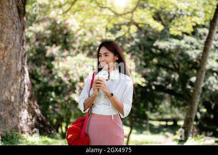 Portrait asian woman with headset hand holding a cup of coffee in the garden Stock Photo