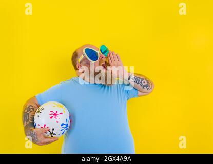 fat man with beard and sunglasses screams with a ball in hand Stock Photo