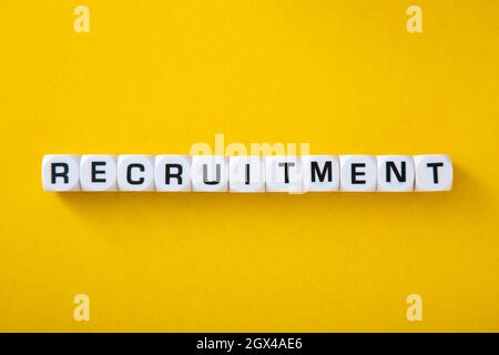 White block with word Recruitment' on yellow background Stock Photo