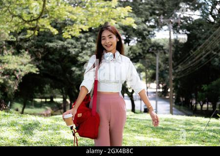 Portrait asian woman with headset hand holding a cup of coffee in ter garden Stock Photo