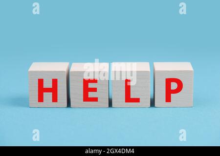 The word help is standing in red letters on wooden cubes, blue colored background Stock Photo