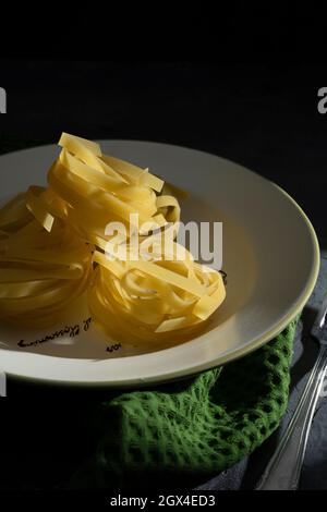 dry pasta on a plate on a black background. Stock Photo