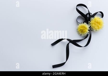 Black funeral ribbon with two yellow flowers. Stock Photo