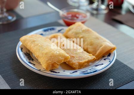 Traditional spring rolls fried on white plate at restaurant.background sweet chili sauce. Stock Photo