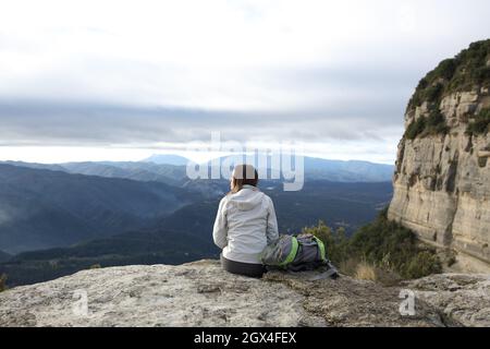 Back view portrait of a trekker sitting in a cliff contemplating Stock Photo