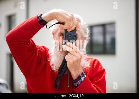 Portrait of bearded senior man photographer with old camera taking photo Stock Photo