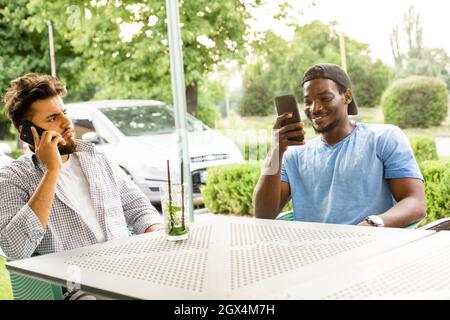 Diverse young friends talking via video call outdoors Stock Photo