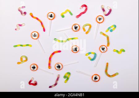 Colorful Halloween candy background with black spiders and jelly worms on white background Stock Photo