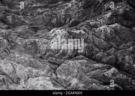 Close-up of a rough and rugged rock surface. Looks like a craggy landscape from above. Abstract natural textured background in black and white. Stock Photo