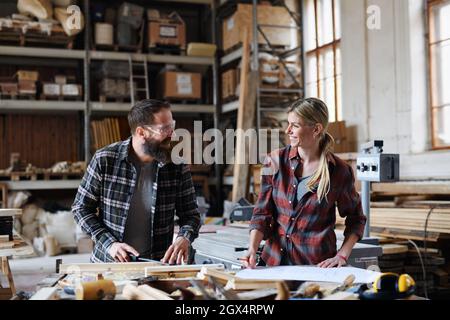 Two carpenters man and woman talking about design of products. Small business concept. Stock Photo