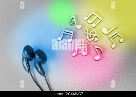 Headphones and wooden musical notes on a white background illuminated with colored spots Stock Photo