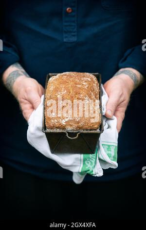 Man holding a homemade loaf of freshly baked Spelt Wholemeal Soda Bread in a tin Stock Photo