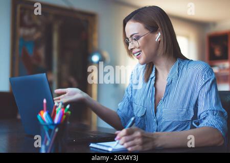 Young entrepreneur making notes during online meeting indoors Stock Photo