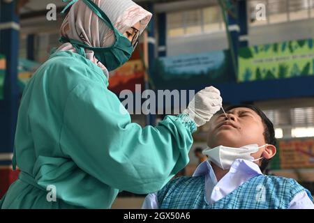 Makassar, Indonesia. 4th Oct, 2021. A medical worker takes a swab sample from a student for nucleic acid test in Makassar, South Sulawesi, Indonesia, Oct. 4, 2021. The number of COVID-19 cases in Indonesia rose by 922 in the past 24 hours to 4,220,206, with the death toll adding by 88 to 142,261, the Health Ministry reported on Monday. Credit: Niaz Sharief/Xinhua/Alamy Live News Stock Photo