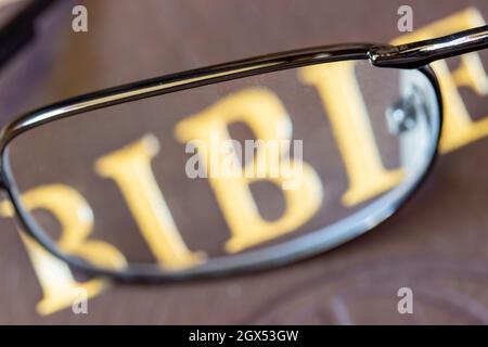 A reading glasses lying on the cover of the Bible, close up. Stock Photo
