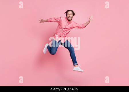 Full length body size view of attractive cheerful guy jumping having fun isolated over pink pastel color background Stock Photo