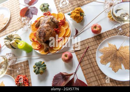 Thanksgiving celebration traditional dinner setting food concept. Top view on roasted turkey on a decorated table. Stock Photo