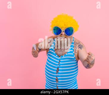 Fat angry man with beard and wig smokes cigarettes Stock Photo