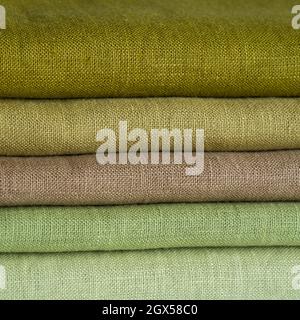 Stack of brown linen fabrics, close up. Green and brown linen background. Stripes of fabric Stock Photo