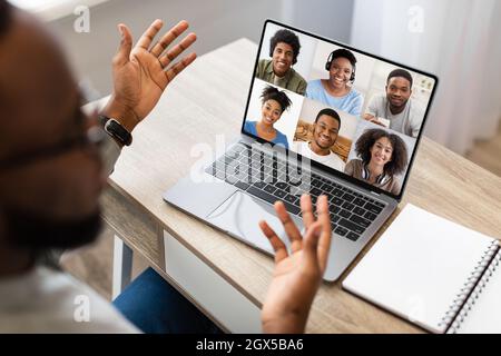Millennial african american man talking with company of friends or family, double exposure on laptop screen Stock Photo